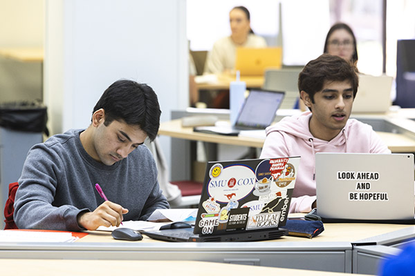 two students with their laptops at a library study table